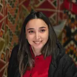 Gunelin gülümsəyən portreti, arxada naxışlı xalça